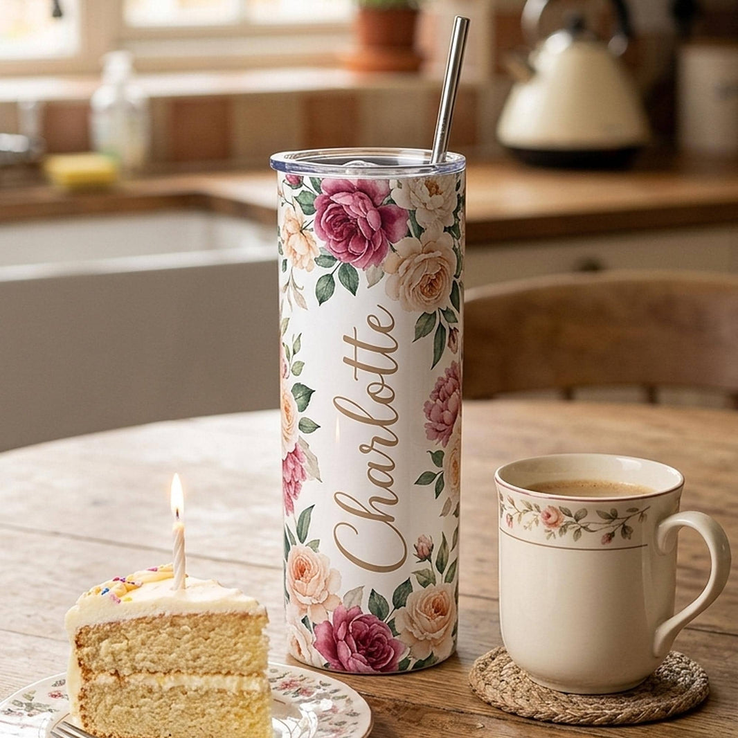 Personalised birthday tumbler printed Charlotte in a pink floral wrap, beside a slice of cake with a candle
