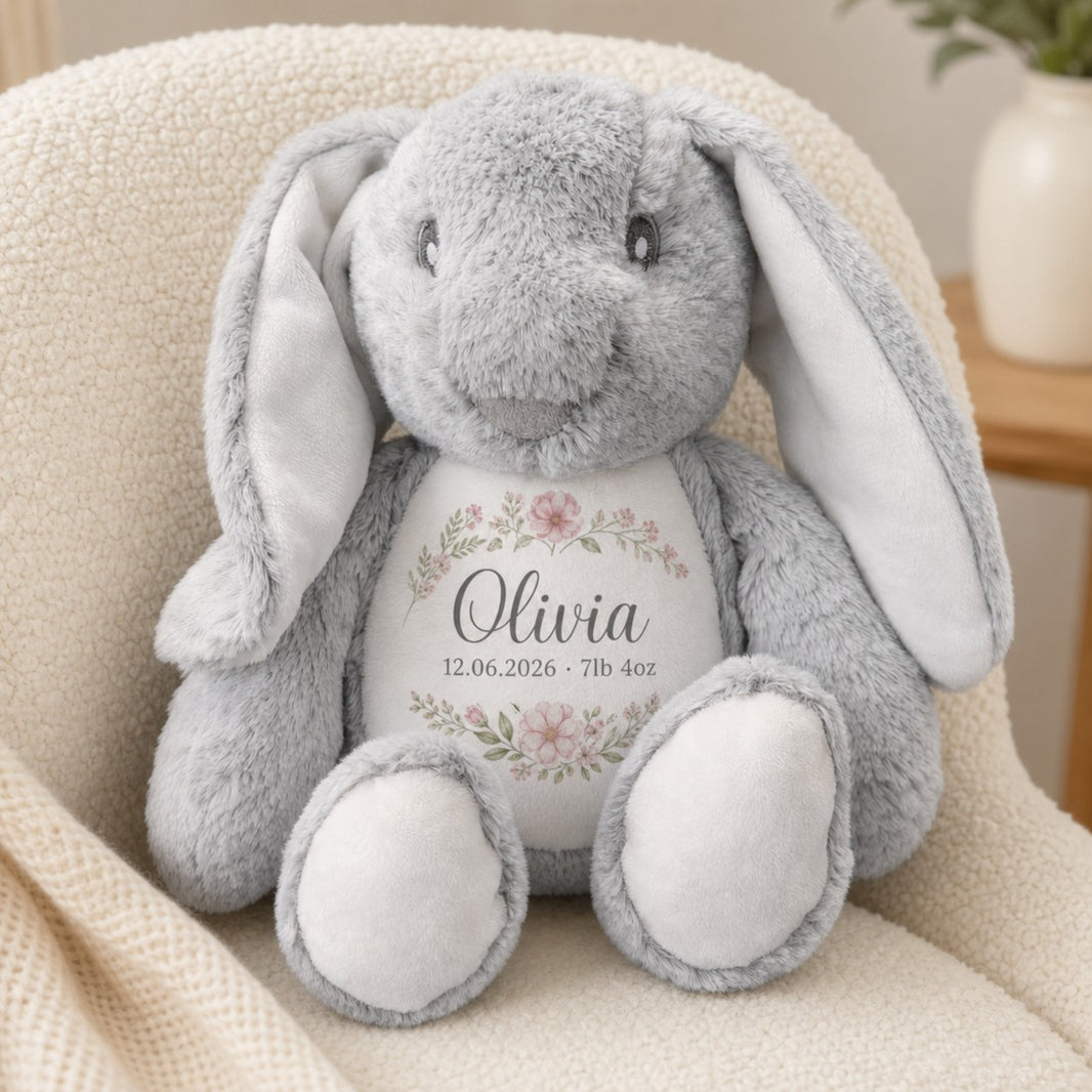 Personalised grey bunny plush toy printed with the name Olivia, birth date and weight in a floral wreath on a nursery chair