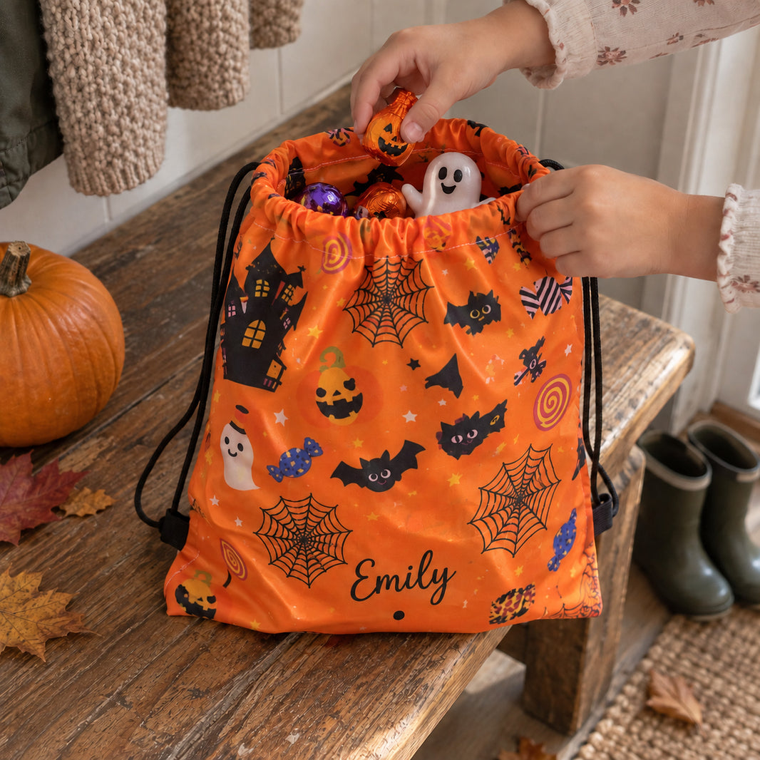 Child's hands filling a personalised Emily trick or treat bag with Halloween sweets on a wooden bench
