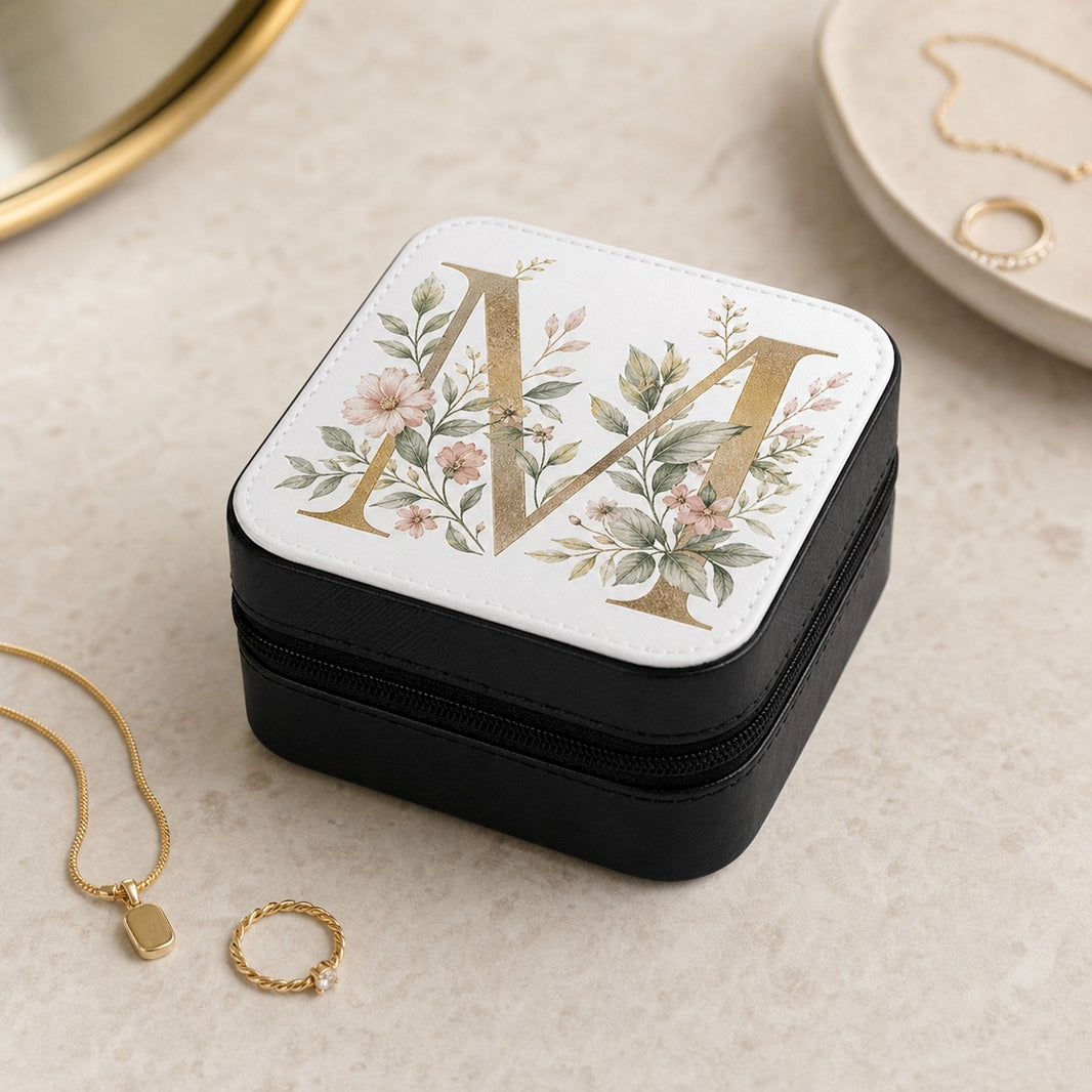 Personalised black jewellery box with gold botanical monogram letter M on the lid beside a gold necklace