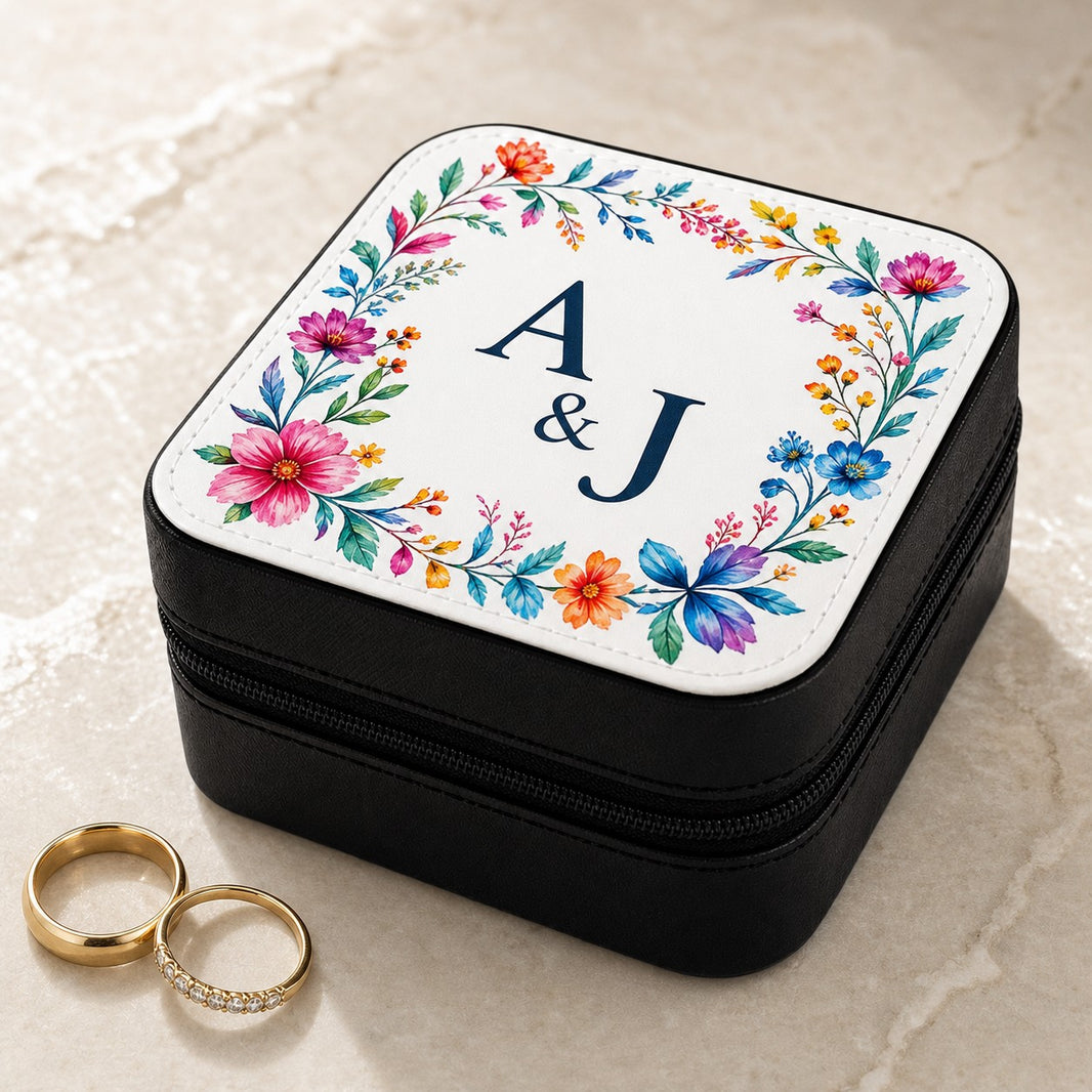 Personalised jewellery box with colourful floral border and couple initials A and J, next to two gold wedding rings