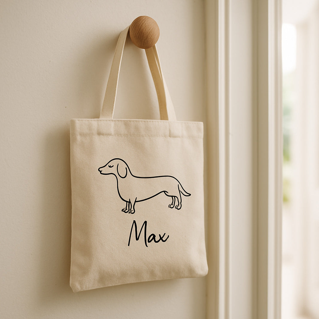 Small personalised canvas tote bag with custom dog line art hanging on a wooden peg in a bright hallway