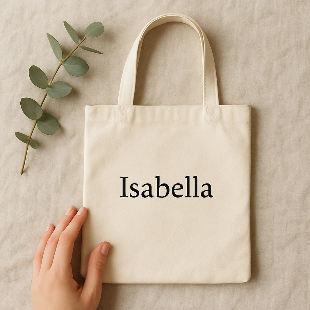 Personalised canvas tote bag printed with the name Isabella, flat lay with eucalyptus