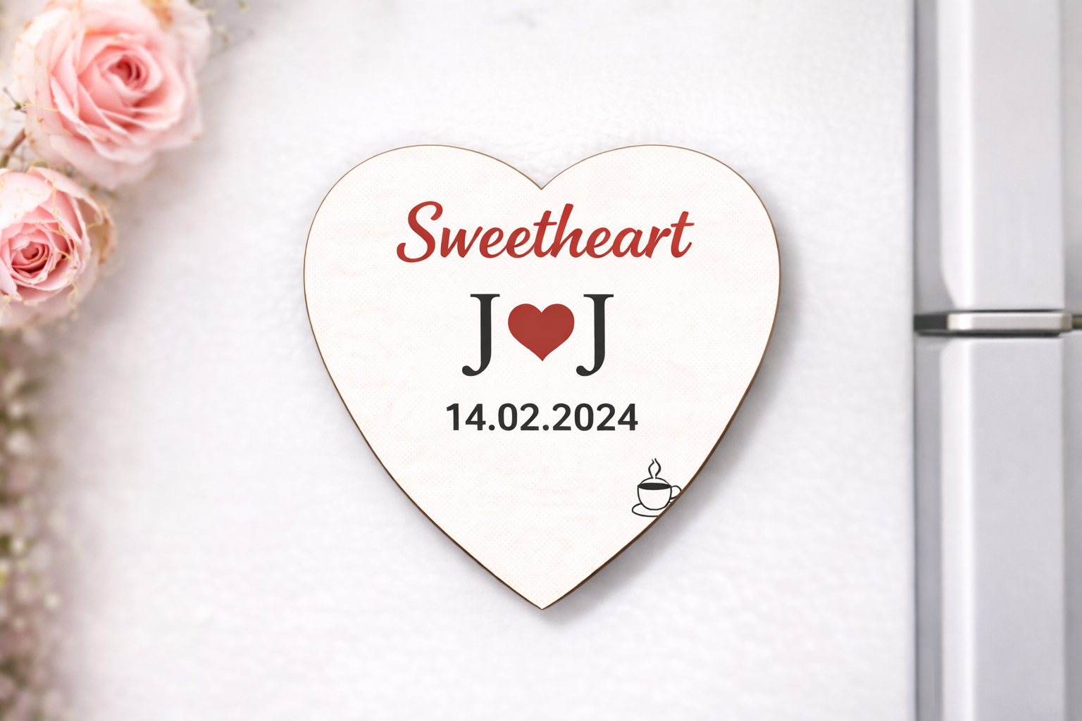 Heart-shaped decorative magnet with 'Sweetheart J O J 14.02.2024' text on a white surface with pink roses.